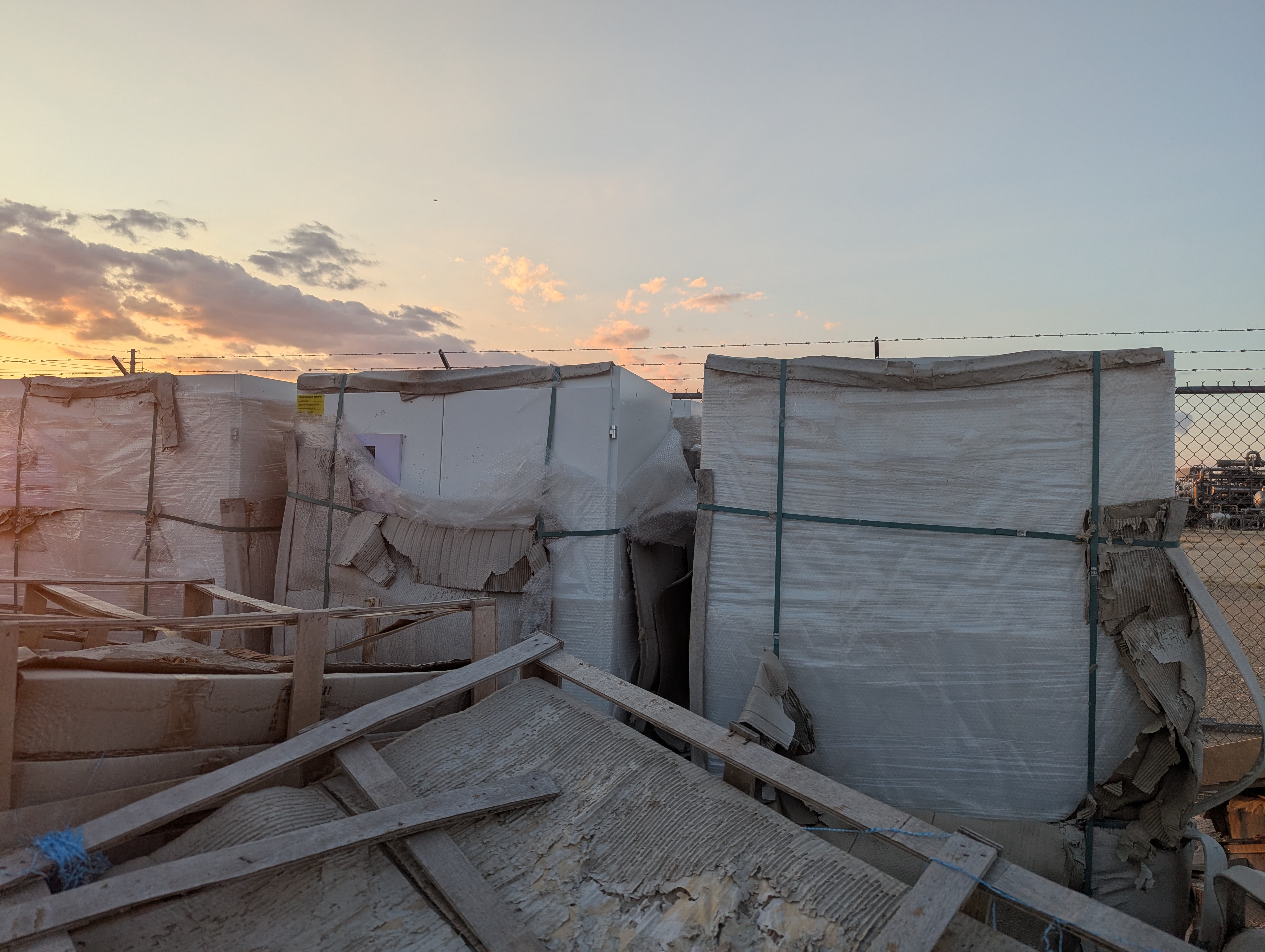 Wrapped modular units stored in a secured yard at sunset